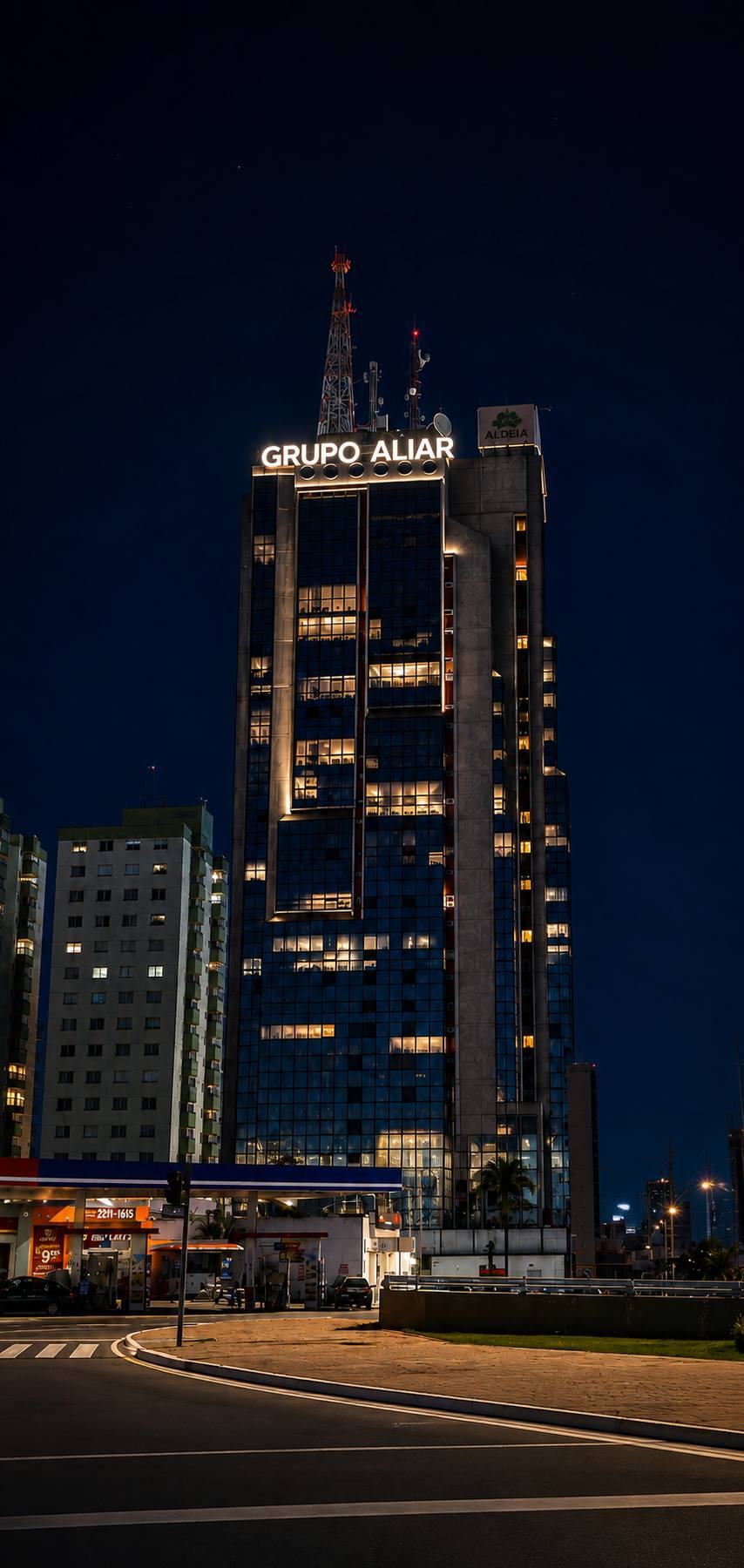 Edif&iacute;cio Aquarius Center &agrave; noite com o letreiro Grupo Aliar iluminado no topo, no Setor Bueno em Goi&acirc;nia