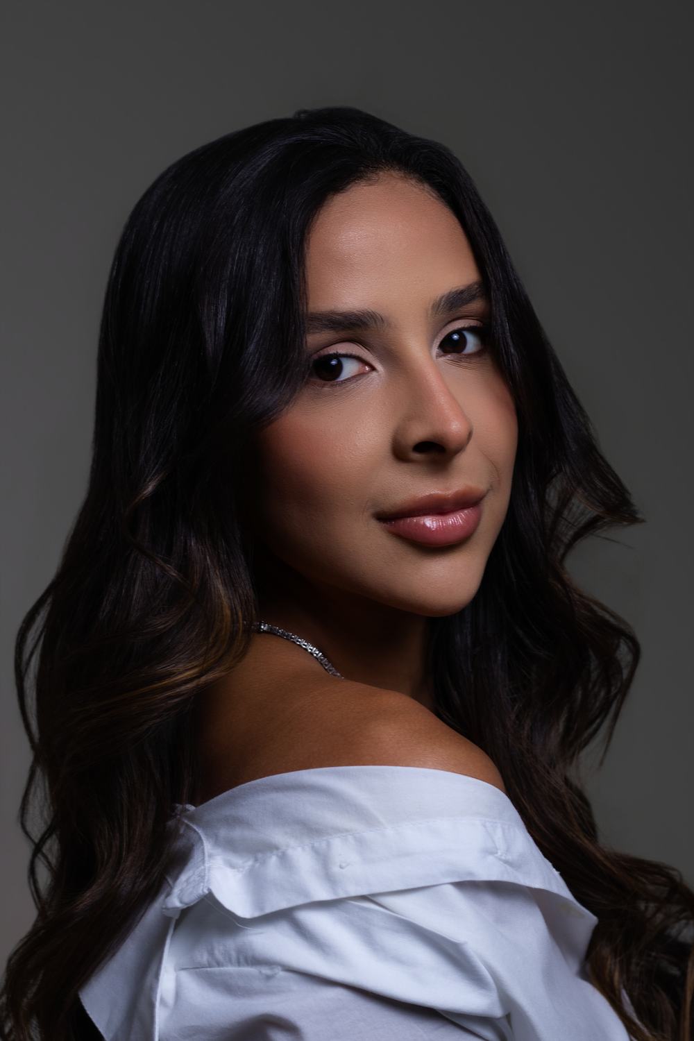 Retrato de posicionamento em close, mulher de camisa branca ombro a ombro e fundo neutro