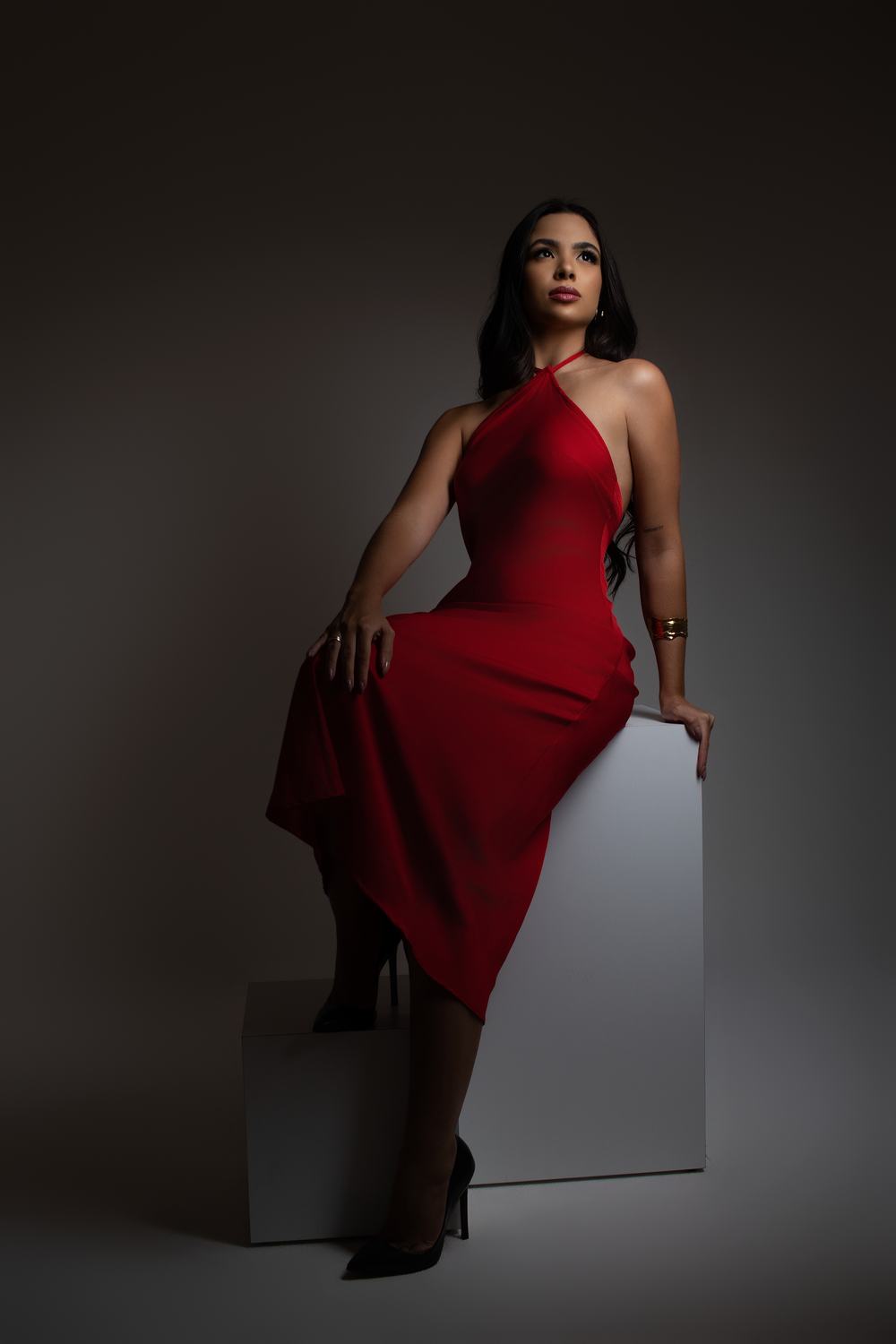 Ensaio de posicionamento de imagem: mulher de vestido vermelho em fundo escuro com luz recortada, por Gabriela Franco