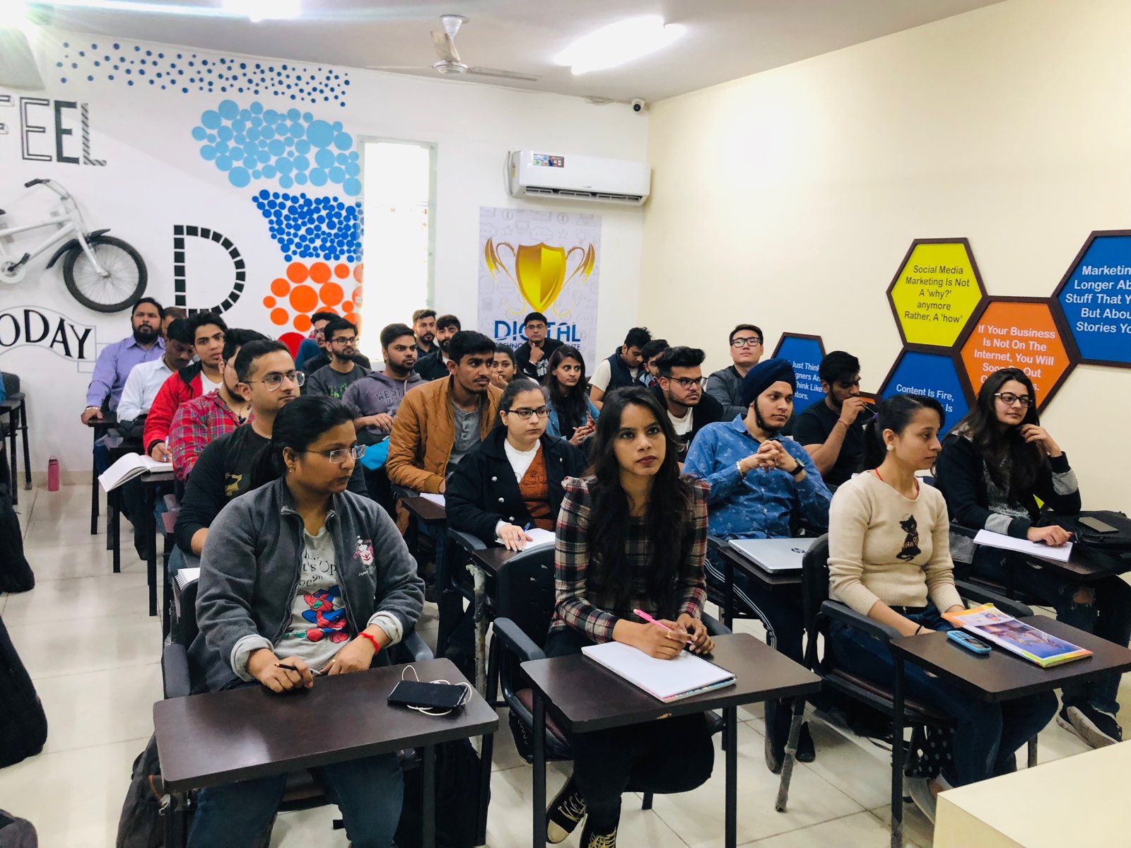 Grupo de pessoas reunidas num workshop de Google Ads, olhando para telas com relatórios de campanha