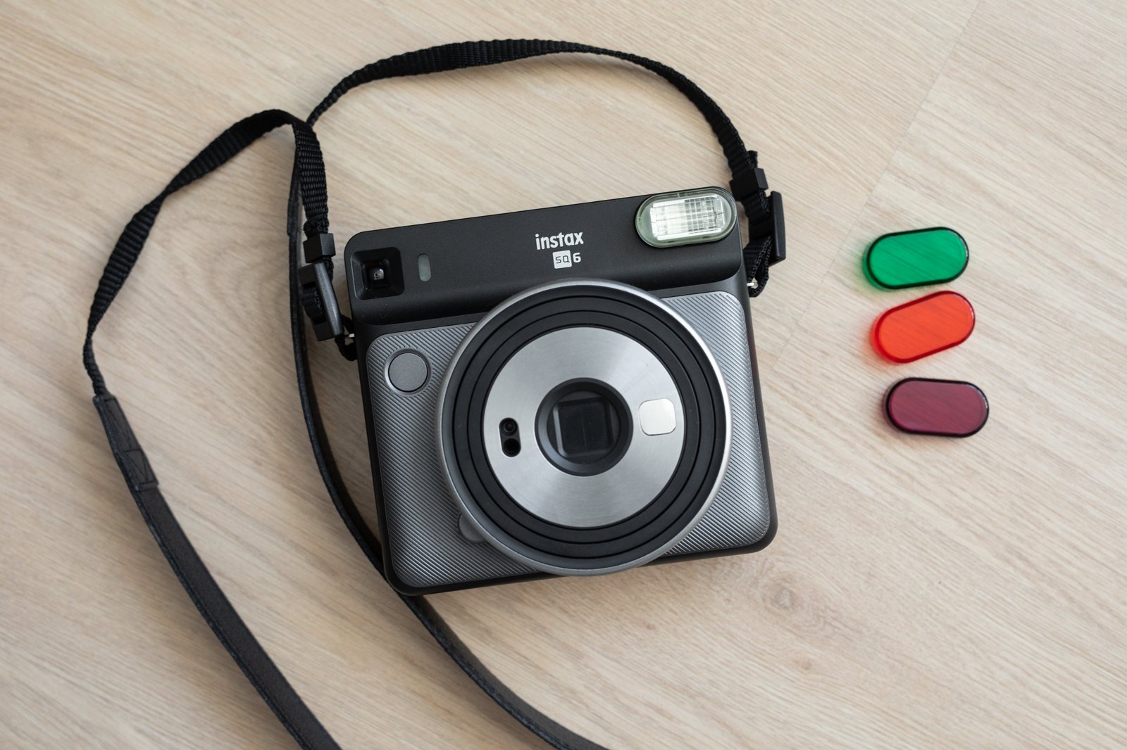 Câmera instantânea Fujifilm instax Square SQ6, modelo anterior da linha quadrada da Fujifilm, sobre uma mesa de madeira