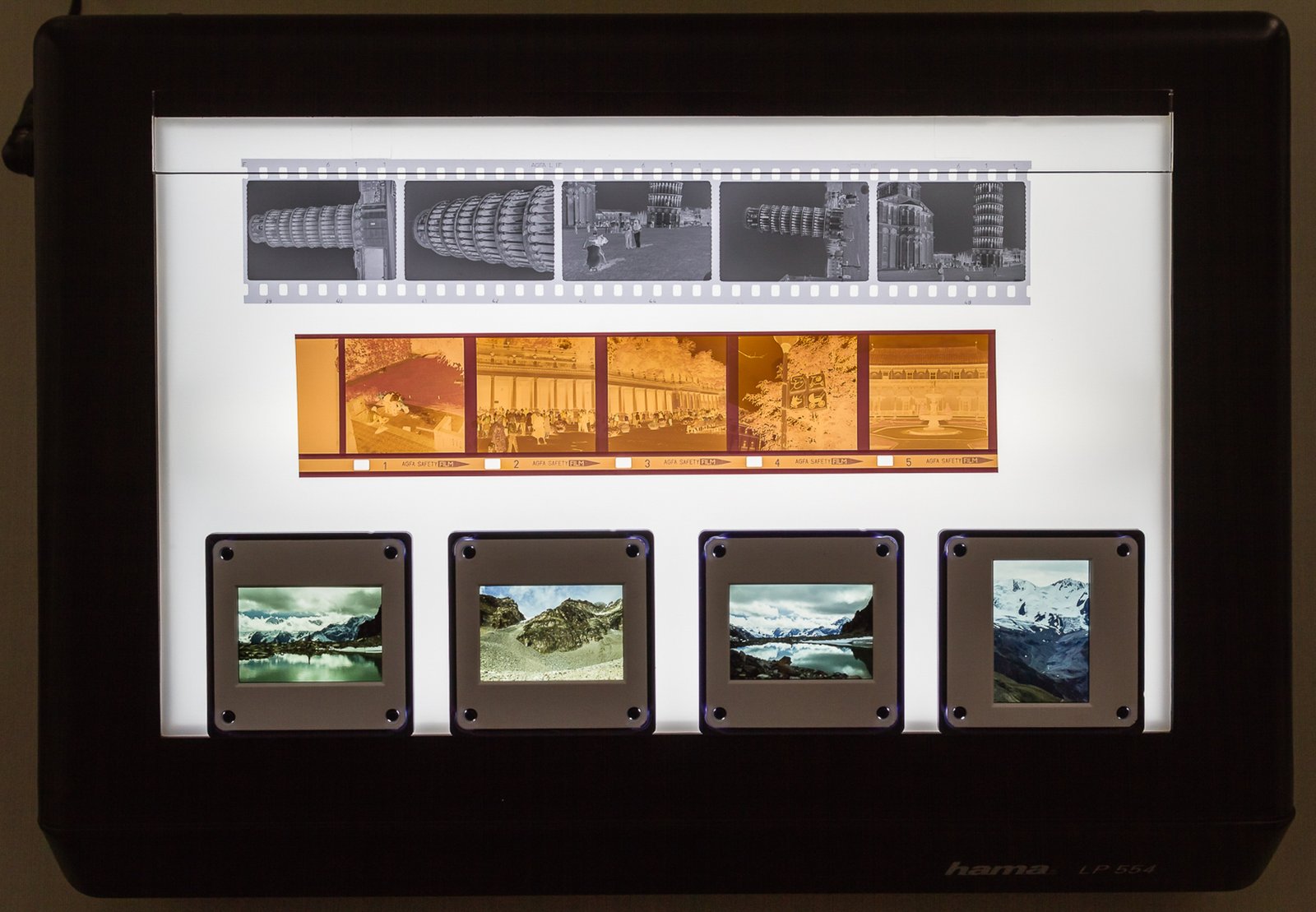 Tiras de negativos fotográficos e slides sobre uma mesa de luz, representando um arquivo de imagens